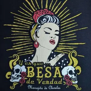 Detalle de la camiseta La Besucona con una mujer de estética pin-up, calaveras y rayos dorados