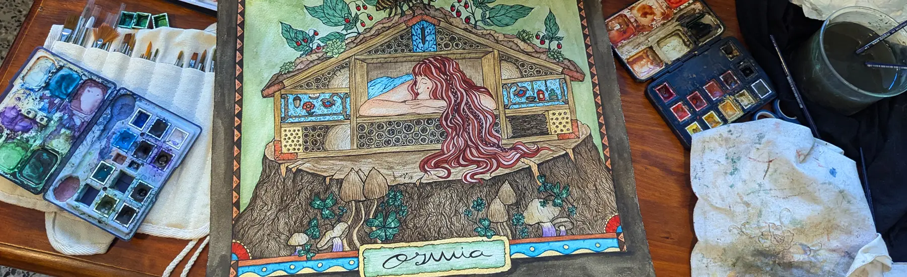 Ilustración de Amaya Barahona sobre una mesa con acuarelas y pinceles